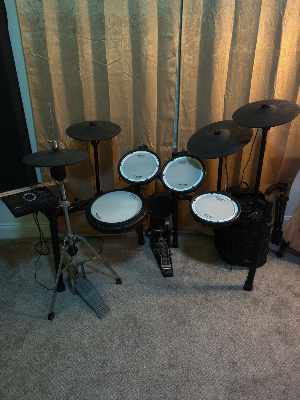 An electronic drum kit set up against the studio curtains.