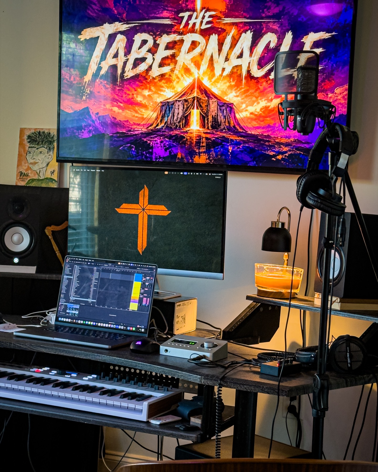 A microphone, headphones, and keyboard at the desk, with The Tabernacle on the screen.